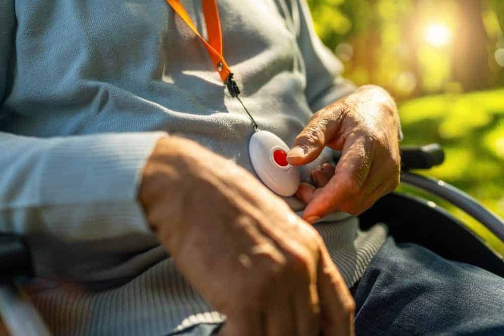 Senior man sitting in a wheelchair holding a safety alarm button - residential care for the elderly