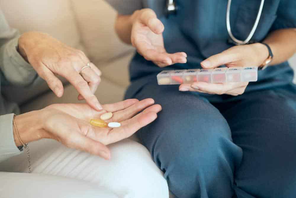 A caregiver teaching a senior person how to manage their medications | at home health care