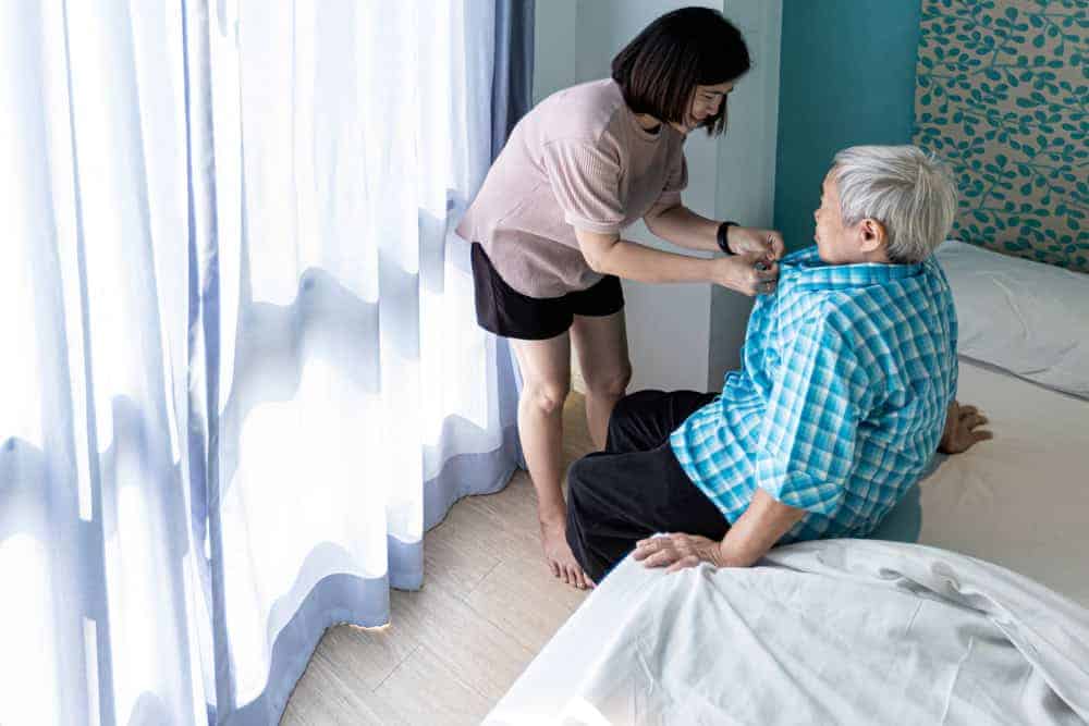 caregiver undressing an older woman to prepare her for bedtime - overnight home care