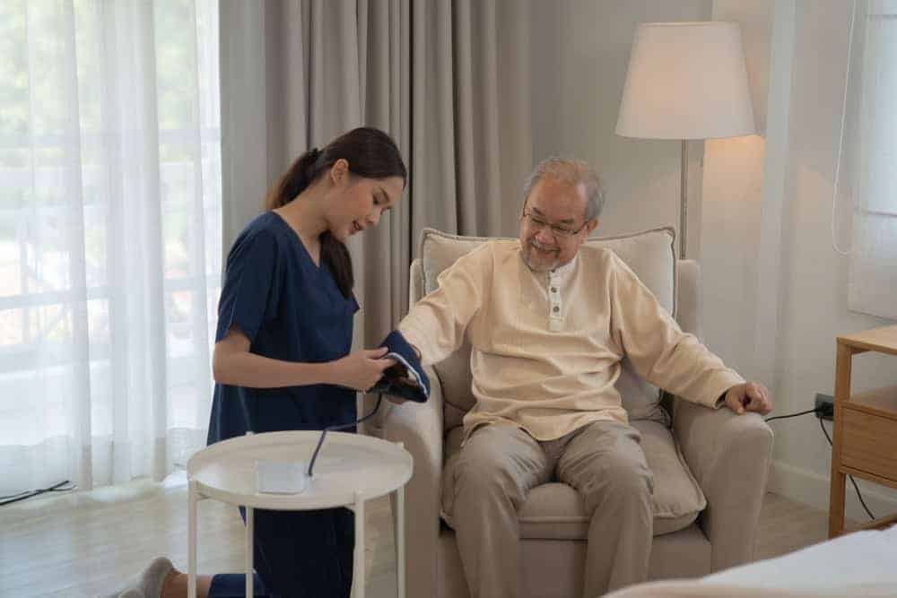 a private home health care nurse monitoring a senior citizen's blood pressure