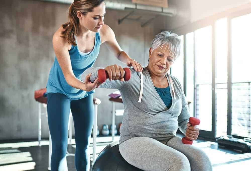 a caregiver helping an older woman with her routine exercises | private care home health