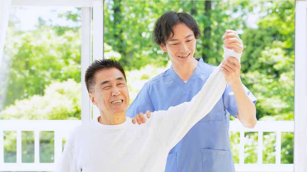 a young nurse assisting his client in moving his aching shoulder | home care program