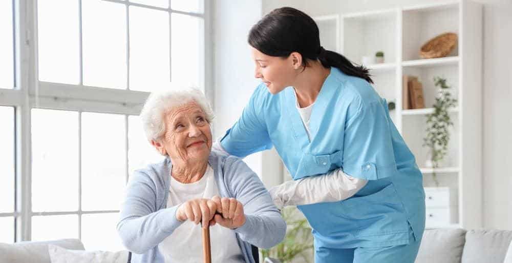 A senior woman and home caregiver smiling - how much does a caregiver cost