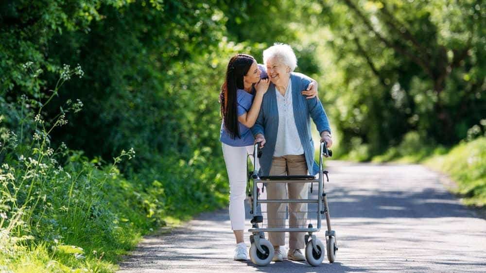 A caregiver assisting an older woman with her morning walks | home aide services