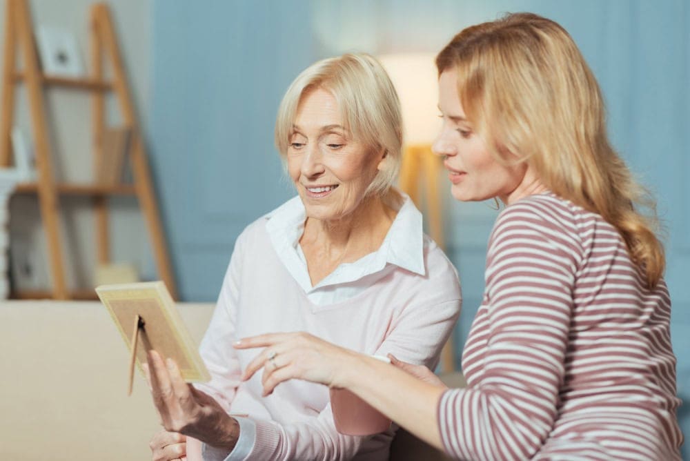 caregiver looking at a frame with an elderly woman | care facilities for elderly