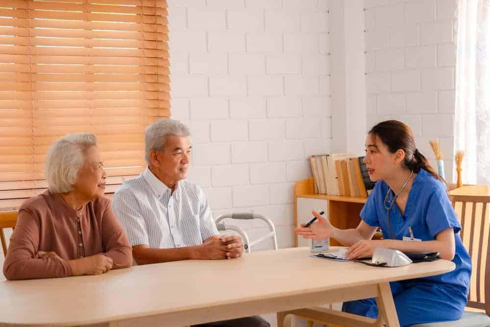 senior couple discussing home health care coverage options with the home health aide