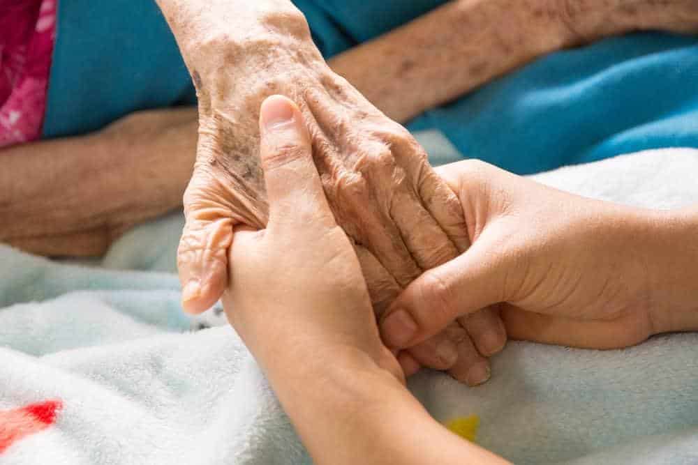 home health caregiver holding the hand of a senior | how to pay for home care services