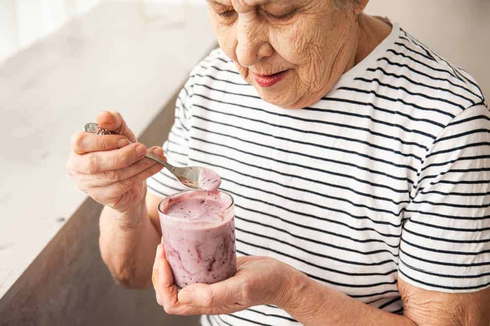 senior woman enjoying yogurt made using ensure