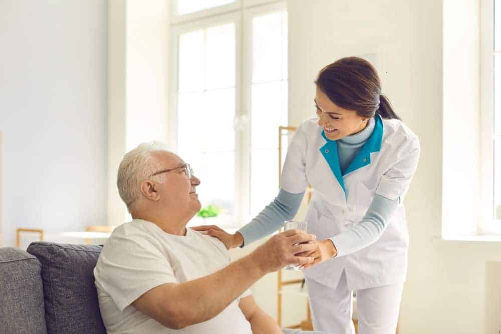 a happy senior at an assisted living home with his caregiver/healthcare infection control