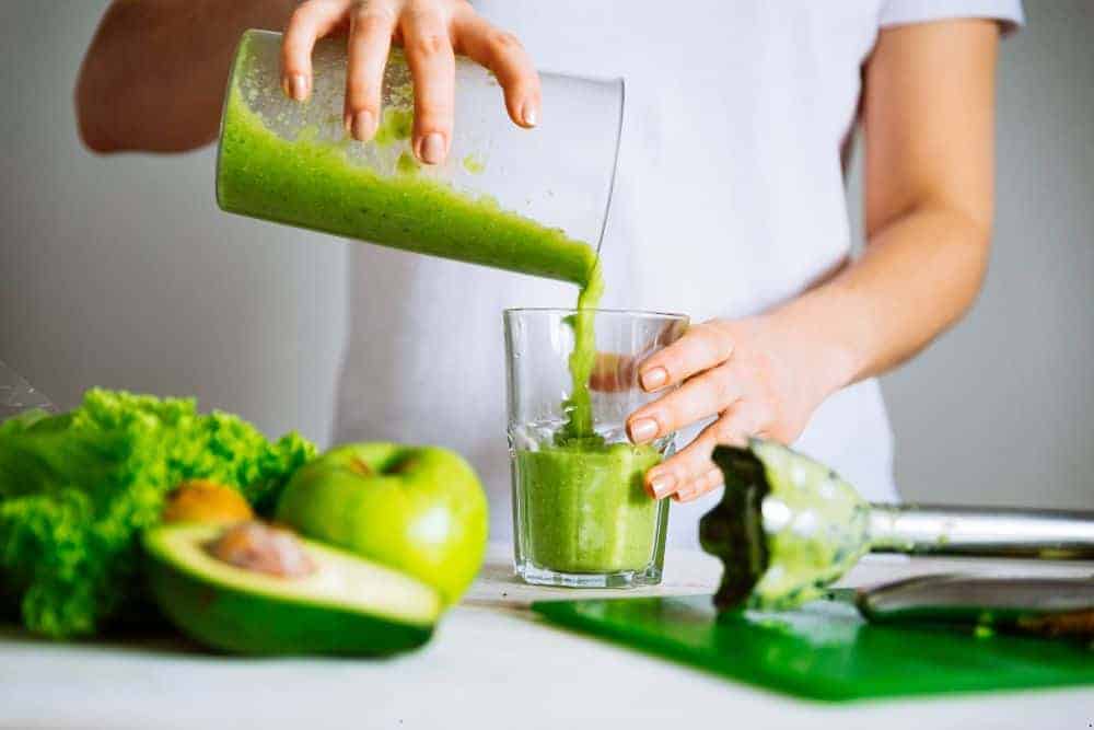 senior woman happily with a glass of green vanilla smoothie and blender | ensure smoothies