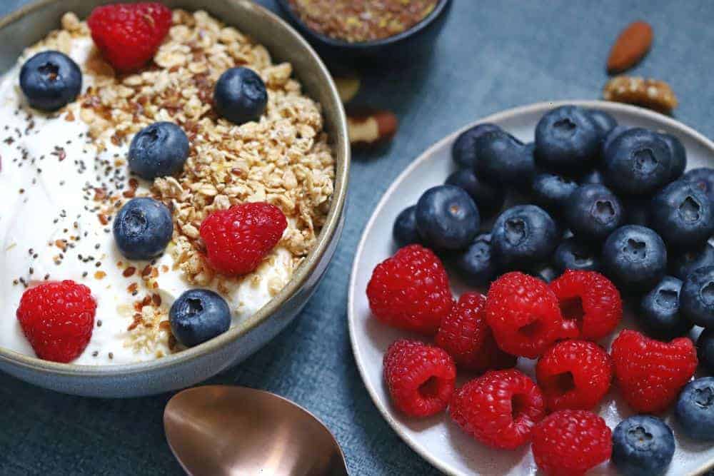 Ensure smoothie bowl with different seeds, yogurt, and raspberries