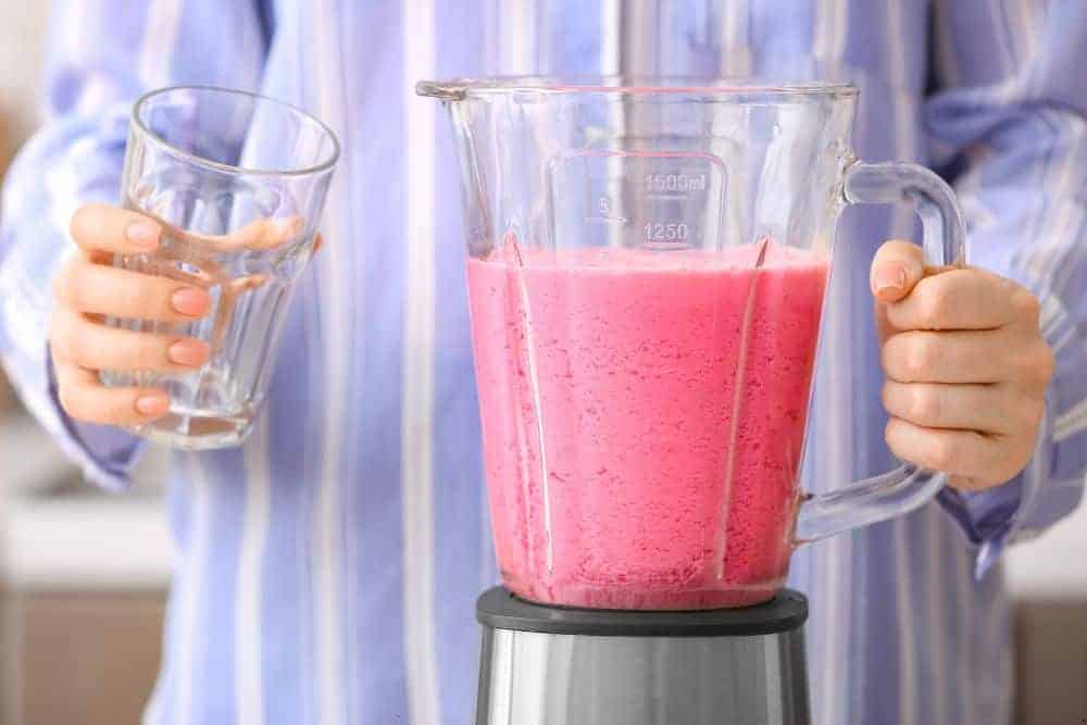 senior blending ingredients of a smoothie in a blender - blend until smooth