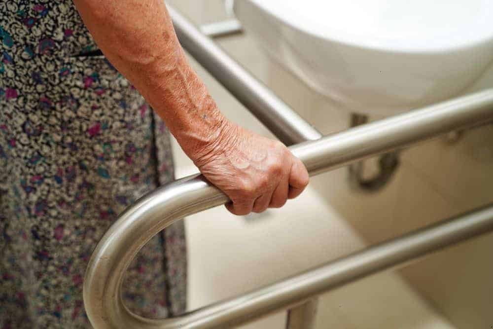 Elderly woman holding bathroom grab bars