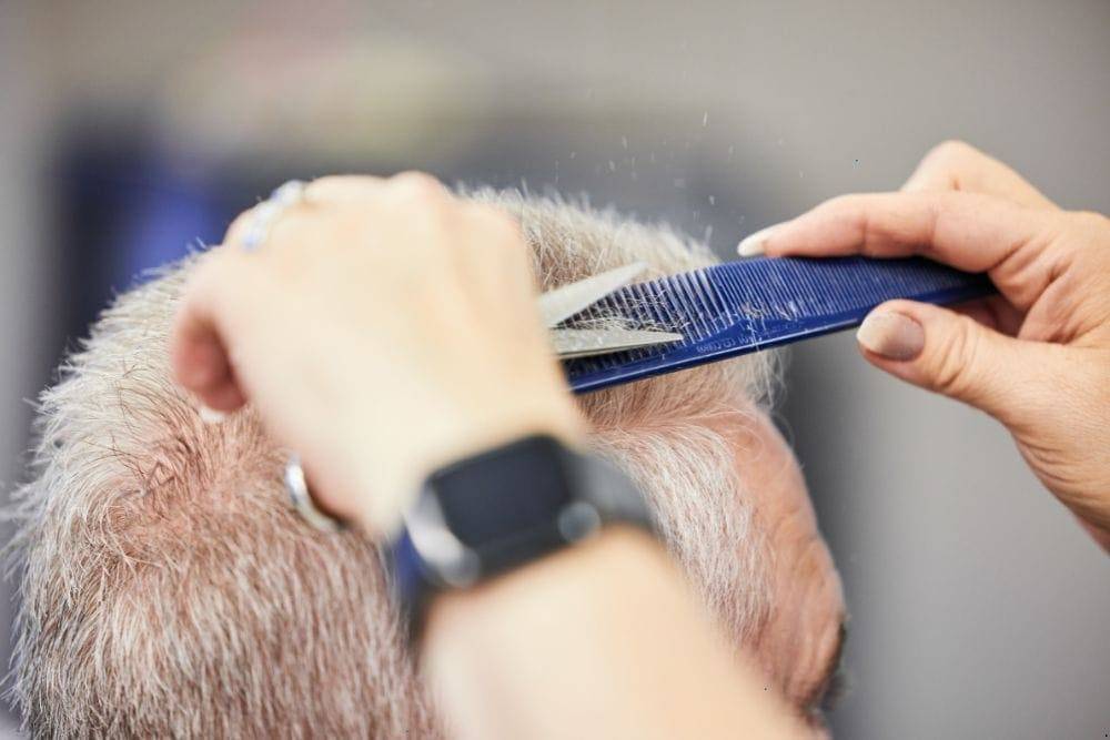 an elderly is getting a haircut as part of personal hygiene