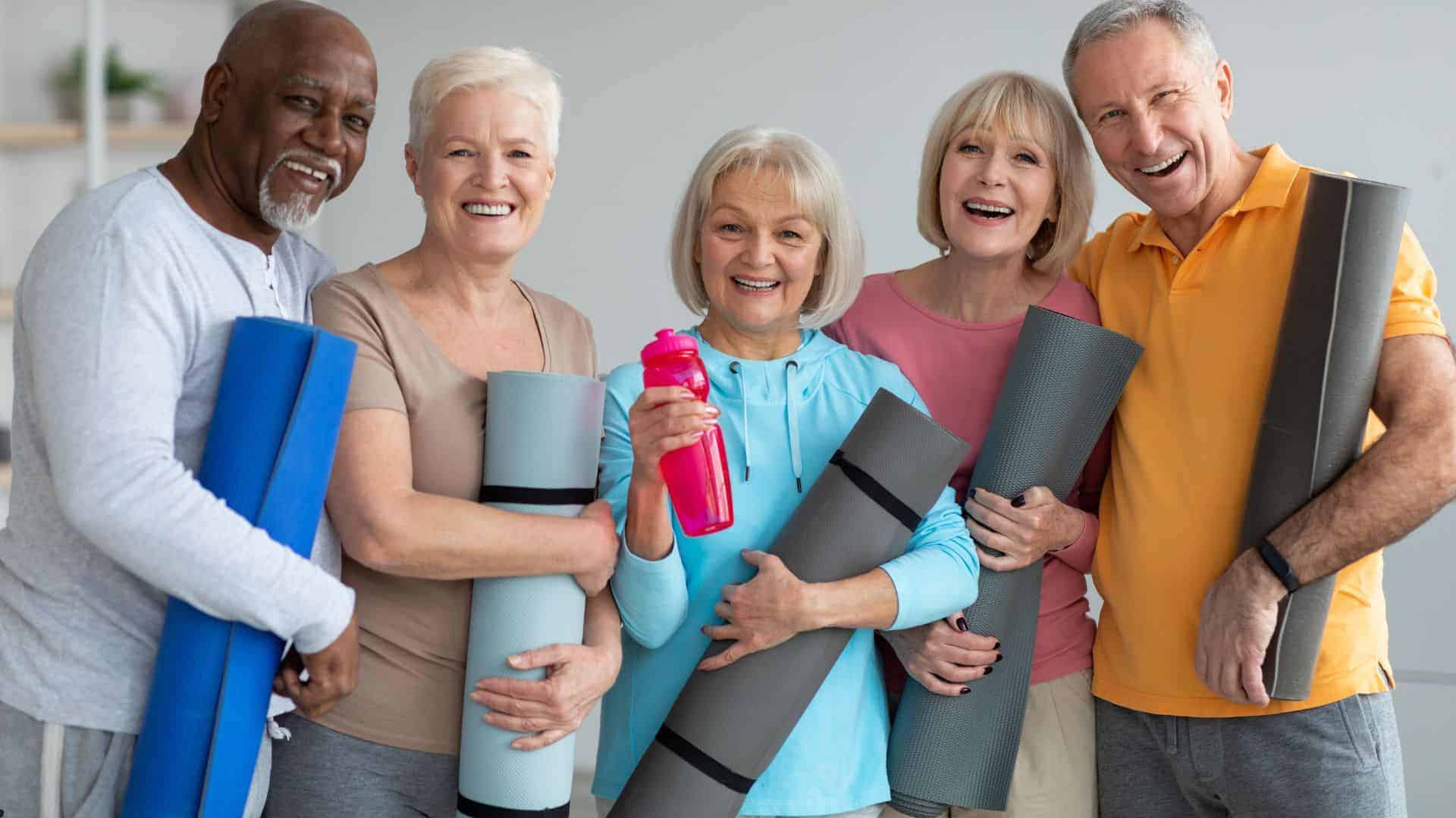 seniors carrying exercise mats and posing after a physical activity