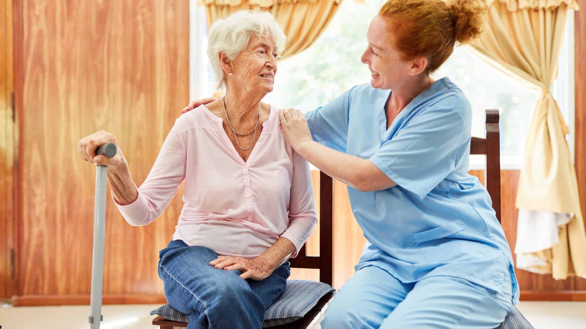 caregiver helping a senior in using a cane to walk