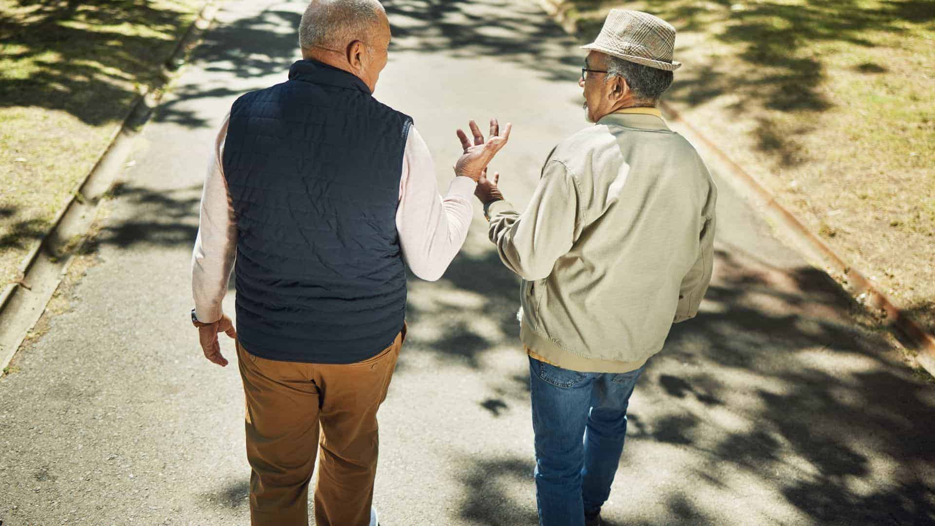 two older gentlemen having a conversation during a walk | socializing is important in combating loneliness in seniors