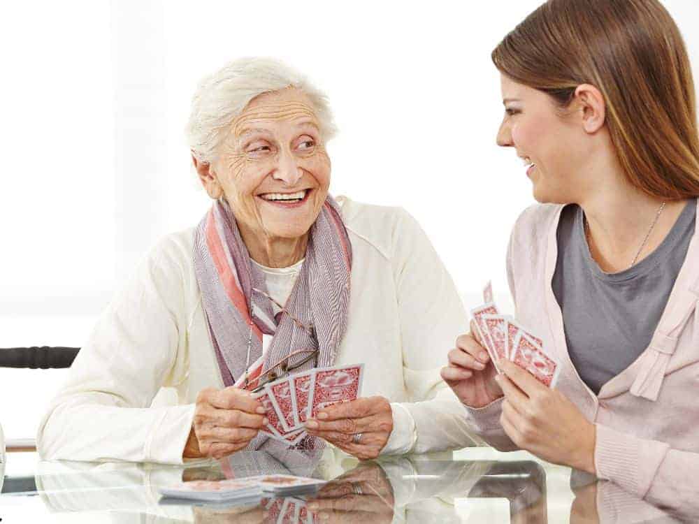 A senior couple playing cards with their caregiver.