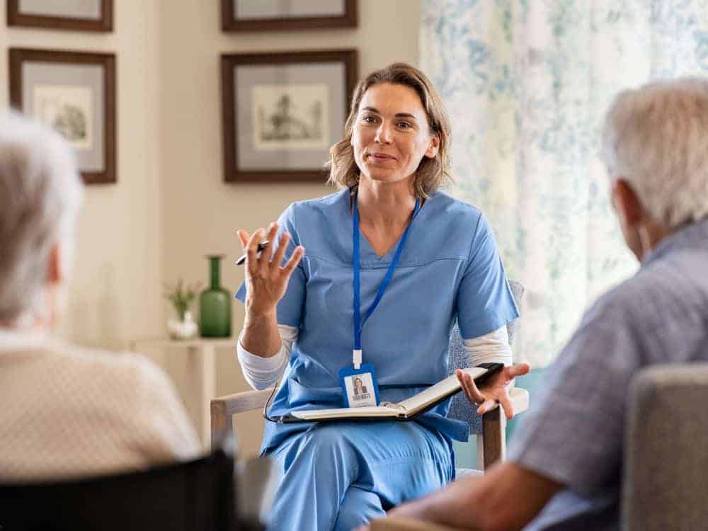 A senior couple talking with a caregiver.
