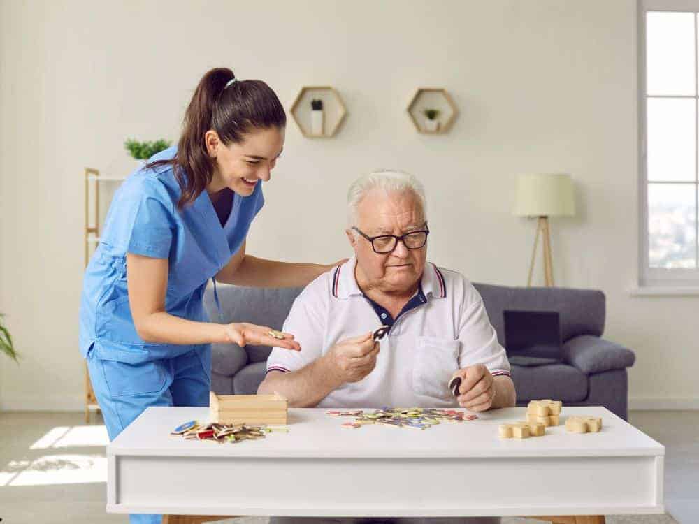 A senior man with dementia playing puzzle with his caregiver.