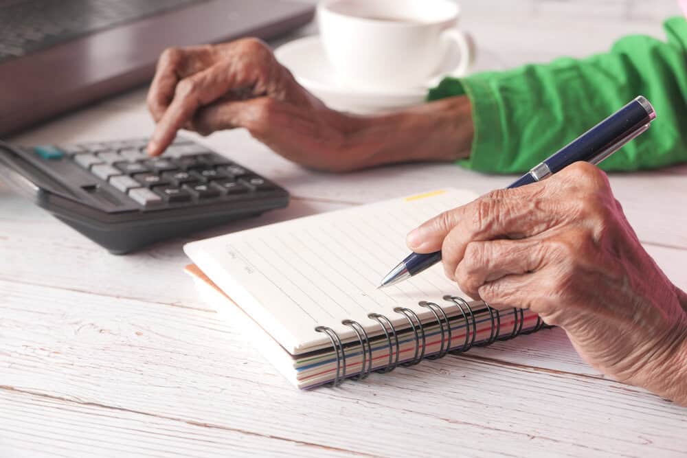 A desk with a calculator and notepad for senior care financial planning.