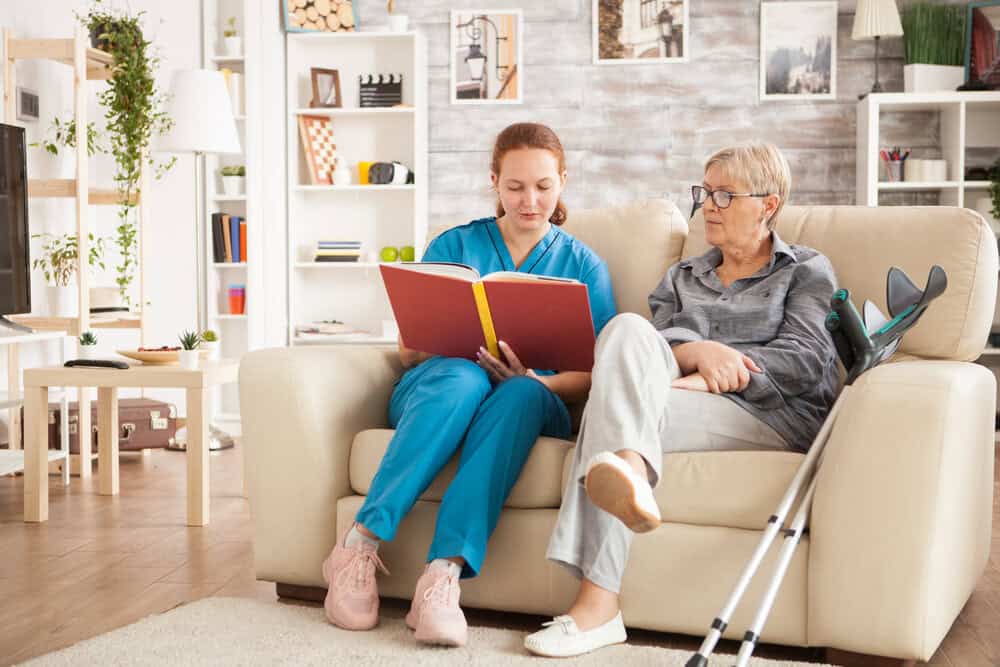 Elderly woman and caregiver looking at a photo album in a comfortable living room, representing quality assisted living care in Nevada.