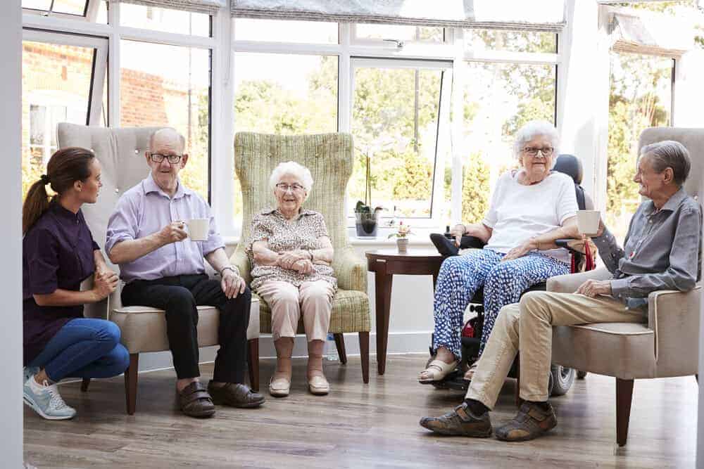 Seniors socializing in a bright, comfortable common room of an assisted living home