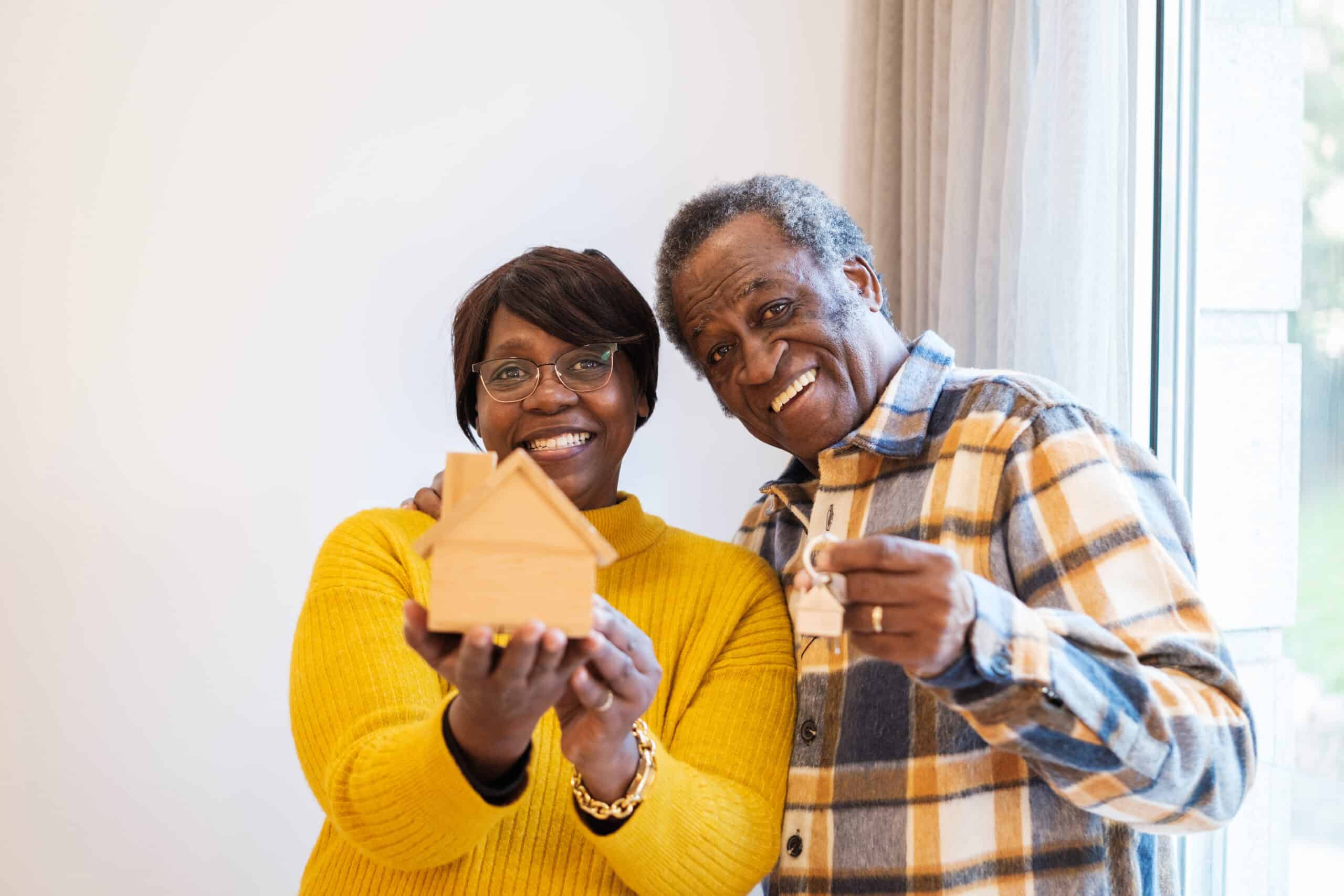 A senior's hands holding a model house, symbolizing the decision to fund senior care with a home sale in Carson City.