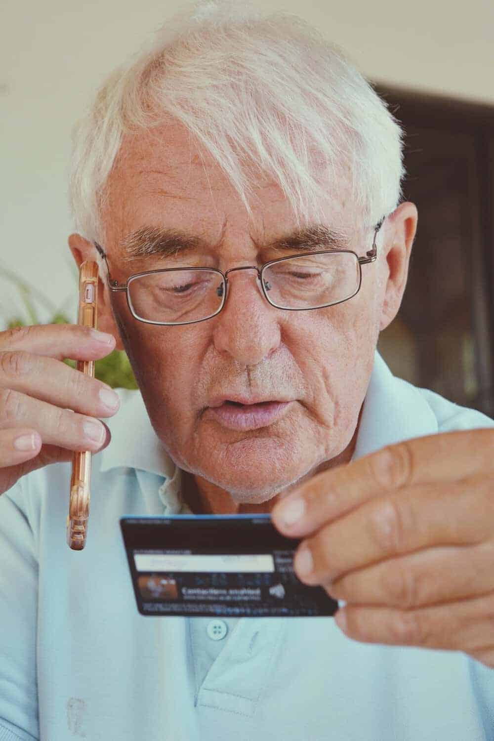 A senior holds an insurance card and phone, ready to call about transportation benefits